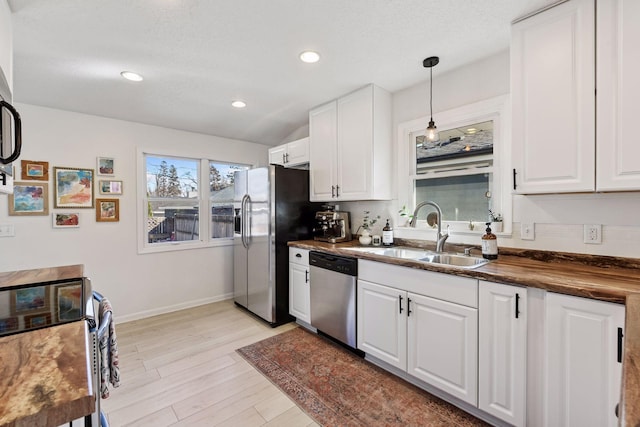 kitchen with baseboards, light wood finished floors, a sink, white cabinets, and appliances with stainless steel finishes