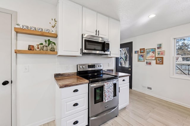 kitchen featuring visible vents, white cabinetry, stainless steel appliances, light wood-style floors, and a textured ceiling