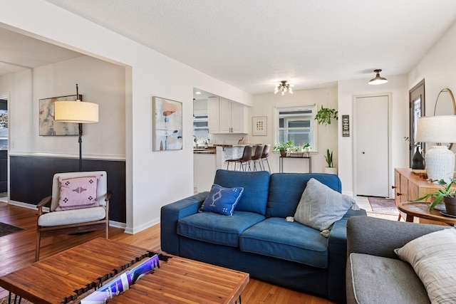 living area with light wood finished floors, a textured ceiling, and baseboards