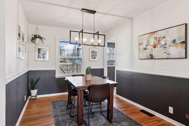 dining area with an inviting chandelier, wood finished floors, visible vents, and a healthy amount of sunlight