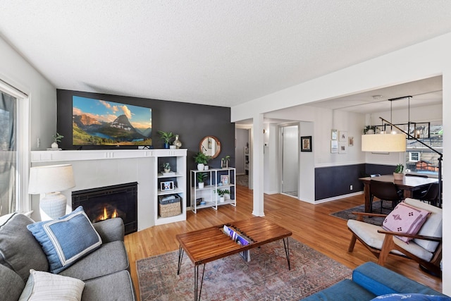 living room featuring a fireplace, a textured ceiling, and wood finished floors