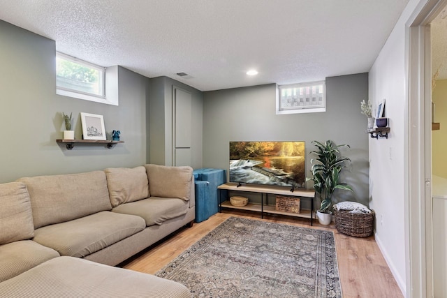 living area featuring baseboards, wood finished floors, visible vents, and a textured ceiling