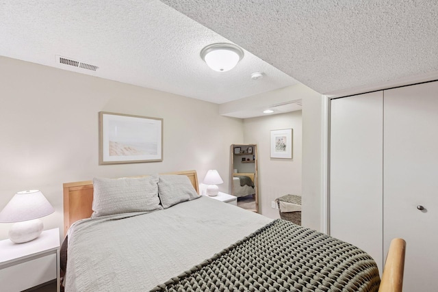 bedroom with visible vents, a textured ceiling, and a closet