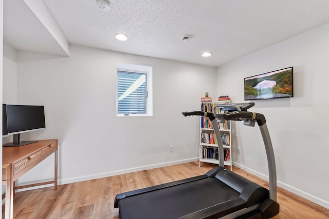 exercise room featuring recessed lighting, wood finished floors, baseboards, and a textured ceiling