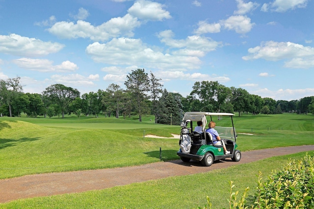 view of home's community featuring a yard, view of golf course, and aphalt driveway