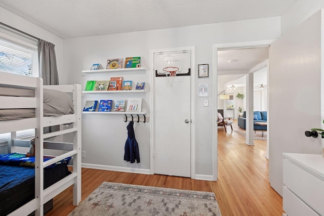 bedroom featuring baseboards, a textured ceiling, and light wood finished floors