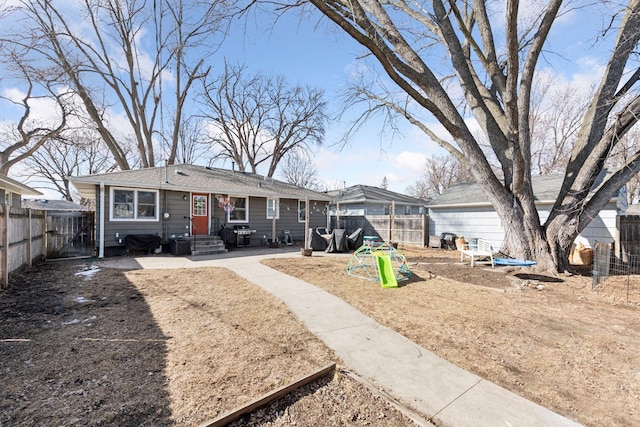 rear view of house with a shingled roof and fence