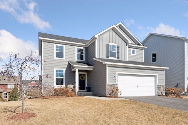 craftsman-style home with board and batten siding, a front lawn, a garage, stone siding, and driveway