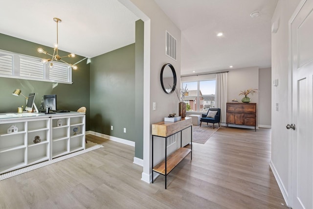 interior space featuring visible vents, baseboards, an inviting chandelier, and wood finished floors