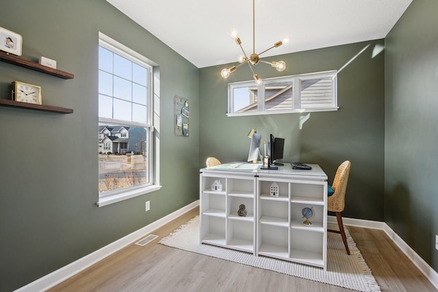 dining area featuring a notable chandelier, visible vents, baseboards, and wood finished floors