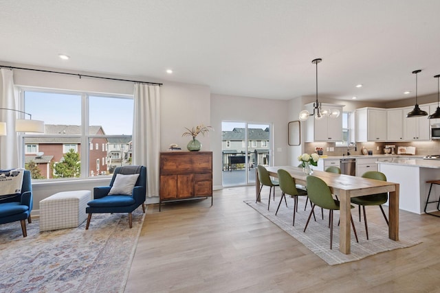 dining space with recessed lighting, an inviting chandelier, and light wood-style floors