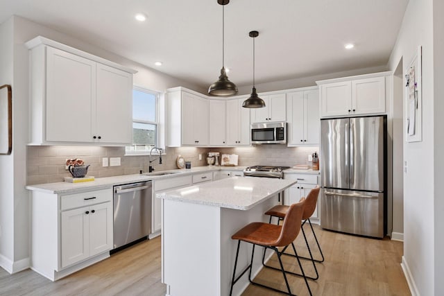 kitchen featuring white cabinetry, light wood-type flooring, appliances with stainless steel finishes, and a sink