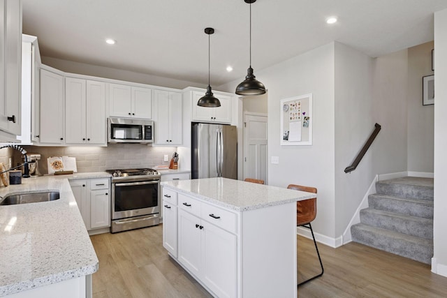 kitchen with a sink, light wood-style floors, backsplash, and stainless steel appliances