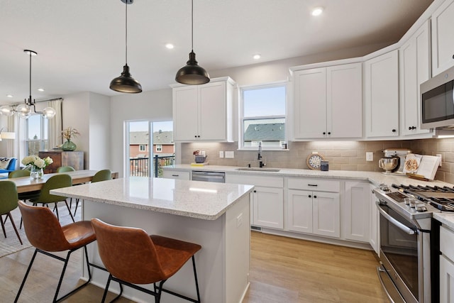 kitchen featuring a sink, decorative backsplash, appliances with stainless steel finishes, and a center island