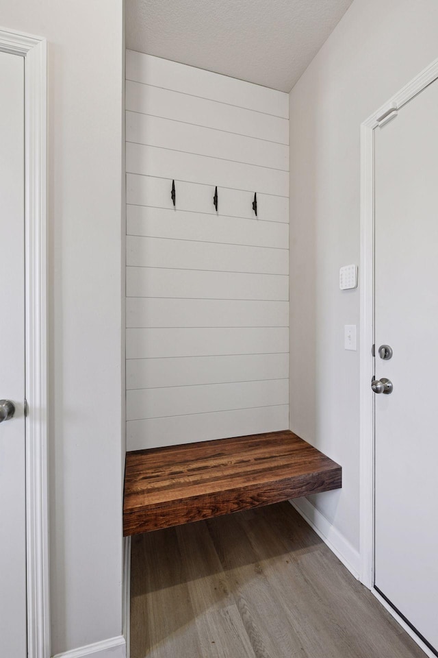 mudroom featuring a textured ceiling, wood finished floors, and wood walls