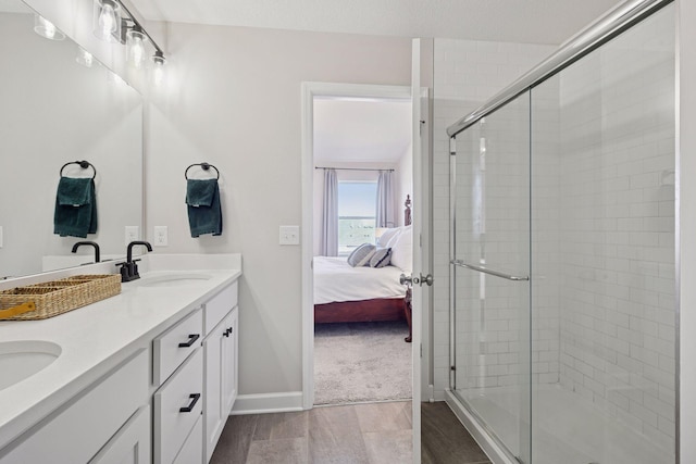 full bathroom featuring a shower stall, connected bathroom, wood finished floors, and a sink