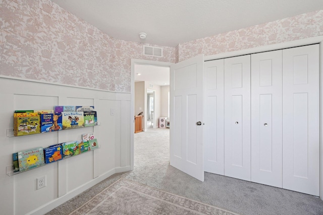 interior space featuring carpet flooring, wainscoting, wallpapered walls, and a decorative wall