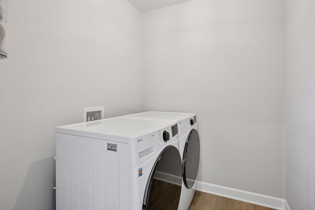 laundry room featuring laundry area, baseboards, light wood-type flooring, and washer and clothes dryer