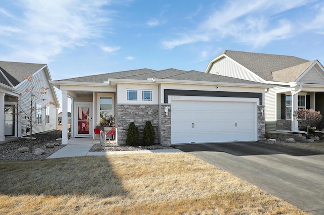 view of front facade with stone siding, an attached garage, a shingled roof, and driveway