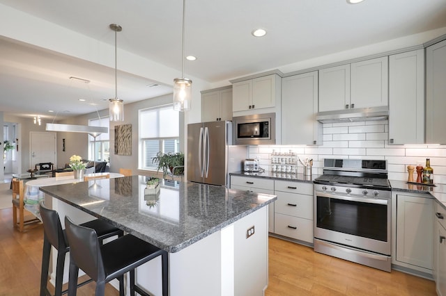 kitchen featuring stainless steel appliances, tasteful backsplash, gray cabinetry, and dark stone counters