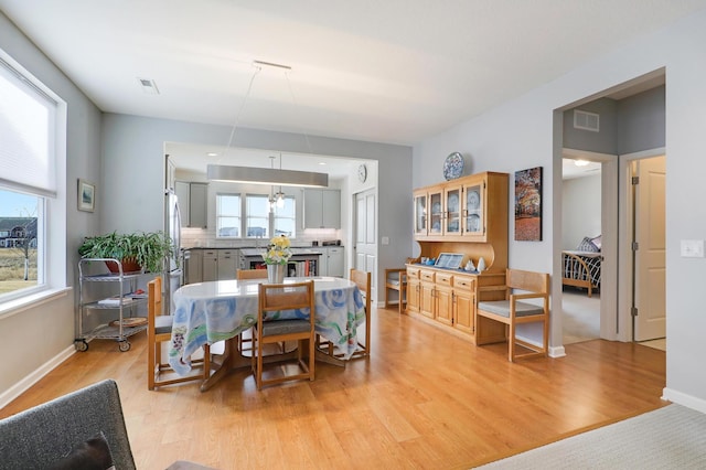 dining space with light wood-style flooring, a healthy amount of sunlight, and visible vents