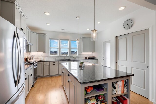 kitchen featuring a sink, decorative backsplash, gray cabinets, appliances with stainless steel finishes, and open shelves