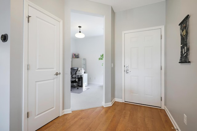 corridor featuring light wood-style flooring and baseboards