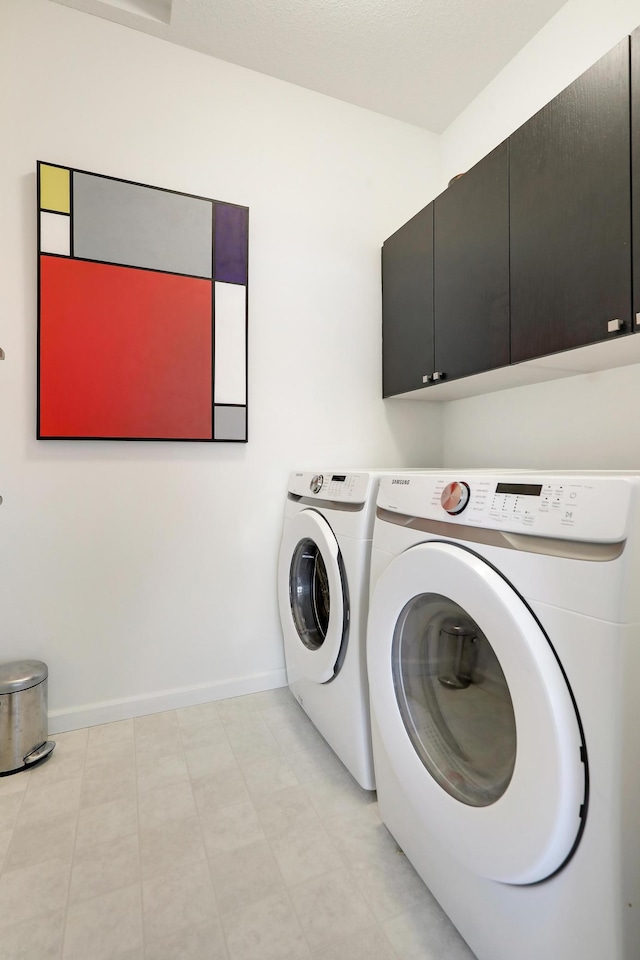 washroom featuring baseboards, cabinet space, and separate washer and dryer