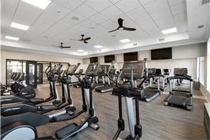 gym featuring a raised ceiling, a ceiling fan, and a paneled ceiling