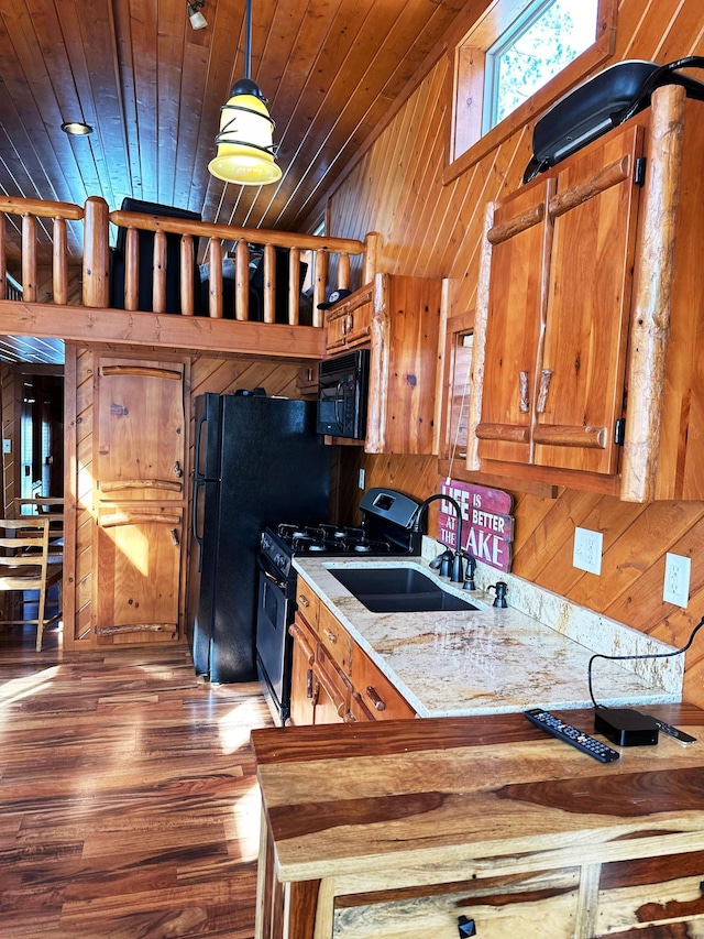 kitchen featuring stainless steel range with gas cooktop, black microwave, wood walls, wooden ceiling, and brown cabinetry