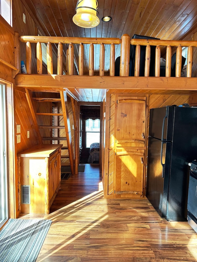 kitchen with wood walls, wood ceiling, freestanding refrigerator, and wood finished floors