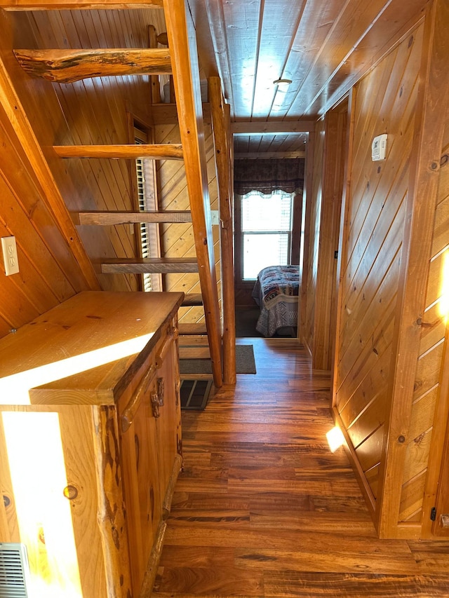 corridor featuring visible vents, wooden walls, wood finished floors, and wooden ceiling