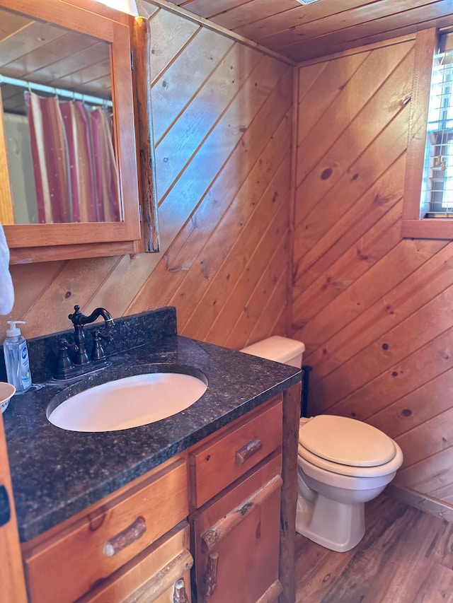 full bathroom with wooden walls, toilet, and wood finished floors