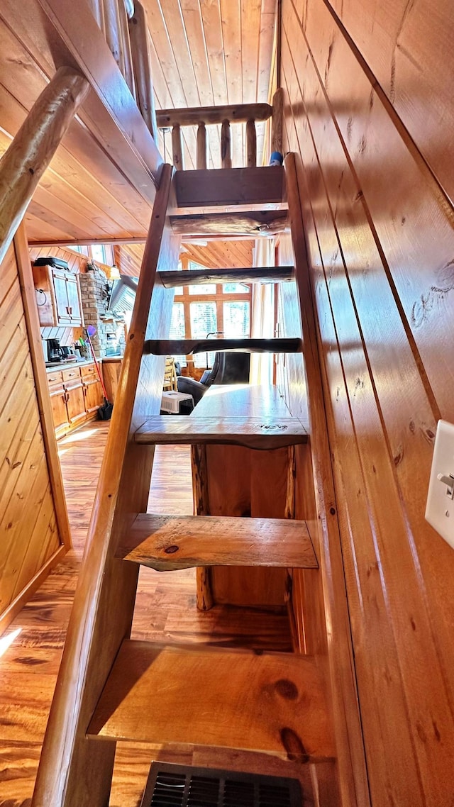 stairs featuring wood walls, wooden ceiling, and hardwood / wood-style flooring