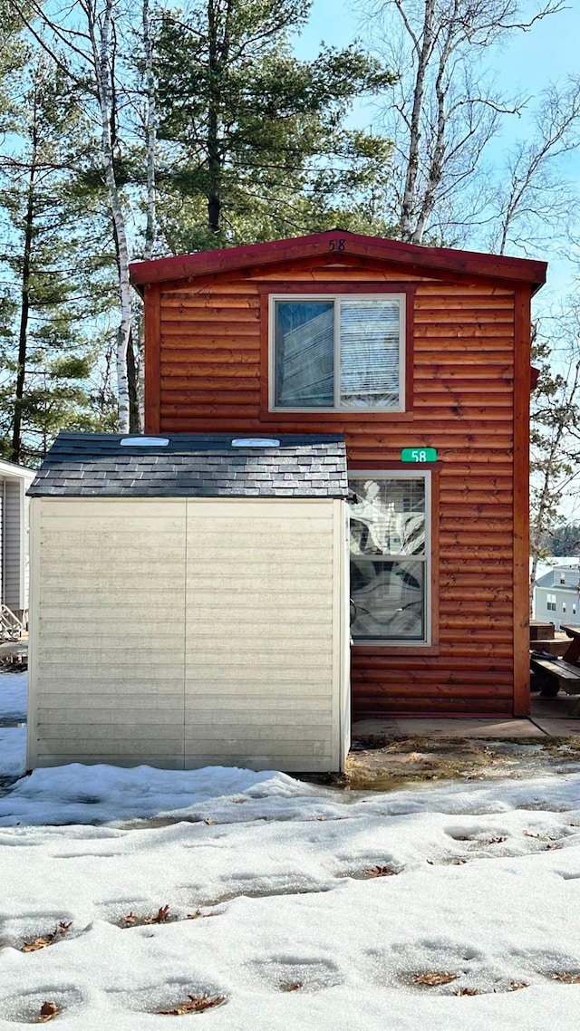 view of snowy exterior with roof with shingles