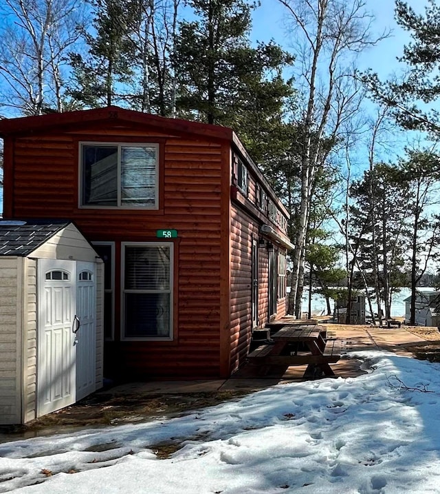 view of snowy exterior with faux log siding