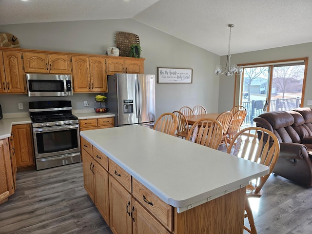 kitchen featuring wood finished floors, stainless steel appliances, an inviting chandelier, light countertops, and vaulted ceiling