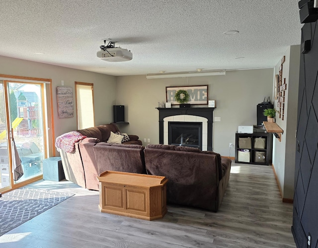 living room featuring wood finished floors, a fireplace, baseboards, and a textured ceiling