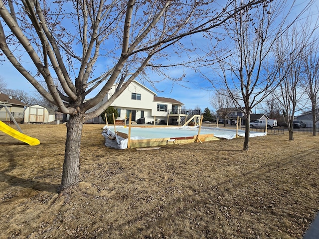 view of yard with an outbuilding, a shed, playground community, and fence