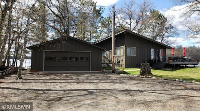 view of front facade featuring a wooden deck, a detached garage, an outbuilding, and board and batten siding