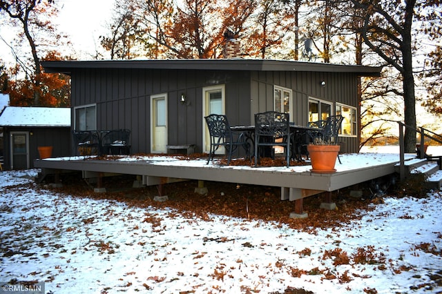 snow covered property featuring board and batten siding and a deck