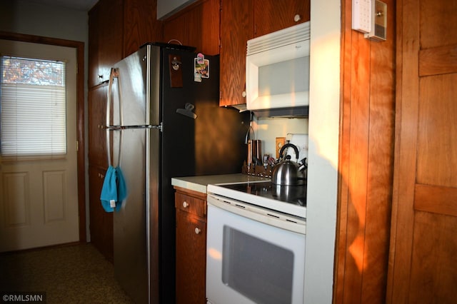 kitchen featuring white appliances, light countertops, and brown cabinets