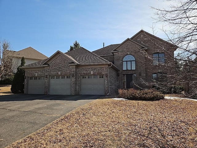 view of front of home featuring a garage, brick siding, roof with shingles, and driveway