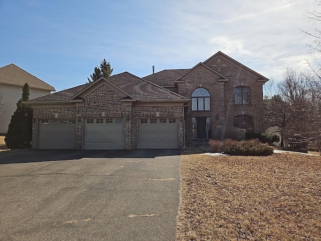 view of front of home with brick siding, driveway, a shingled roof, and a garage