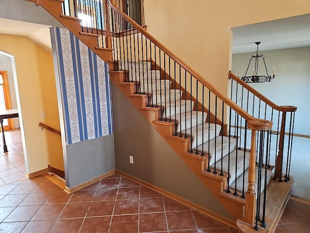 stairway featuring tile patterned floors, baseboards, and a towering ceiling