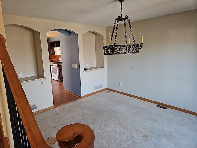 empty room featuring carpet flooring, visible vents, and a textured ceiling