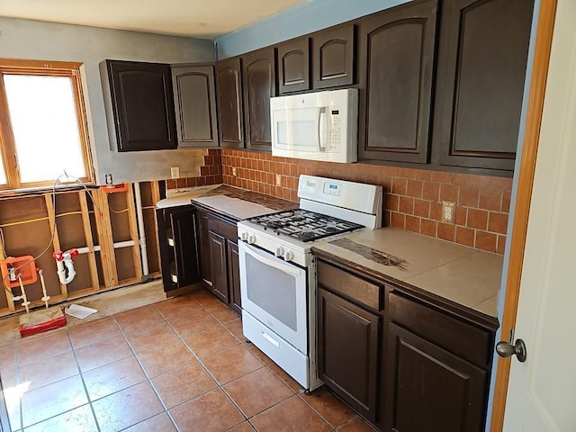 kitchen featuring light tile patterned floors, white appliances, backsplash, and dark brown cabinets