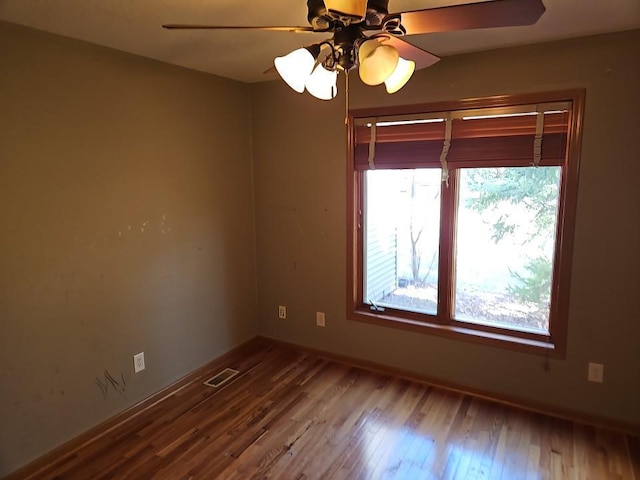 empty room featuring visible vents, baseboards, wood finished floors, and a ceiling fan