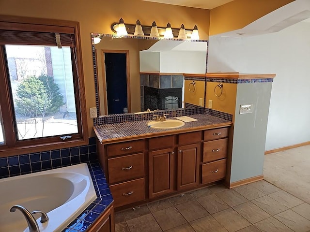 full bathroom featuring vanity, a bath, baseboards, and tile patterned flooring