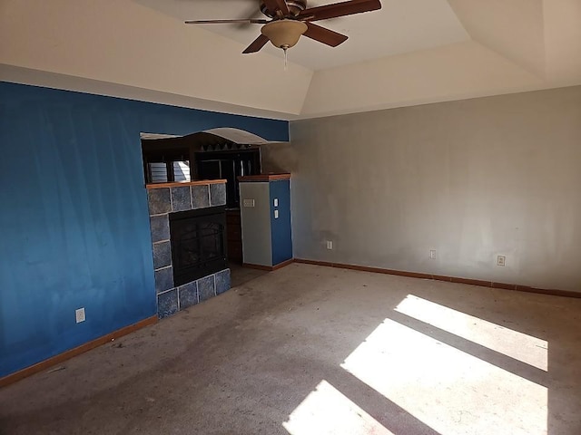 unfurnished living room featuring a tiled fireplace, vaulted ceiling, a ceiling fan, and baseboards